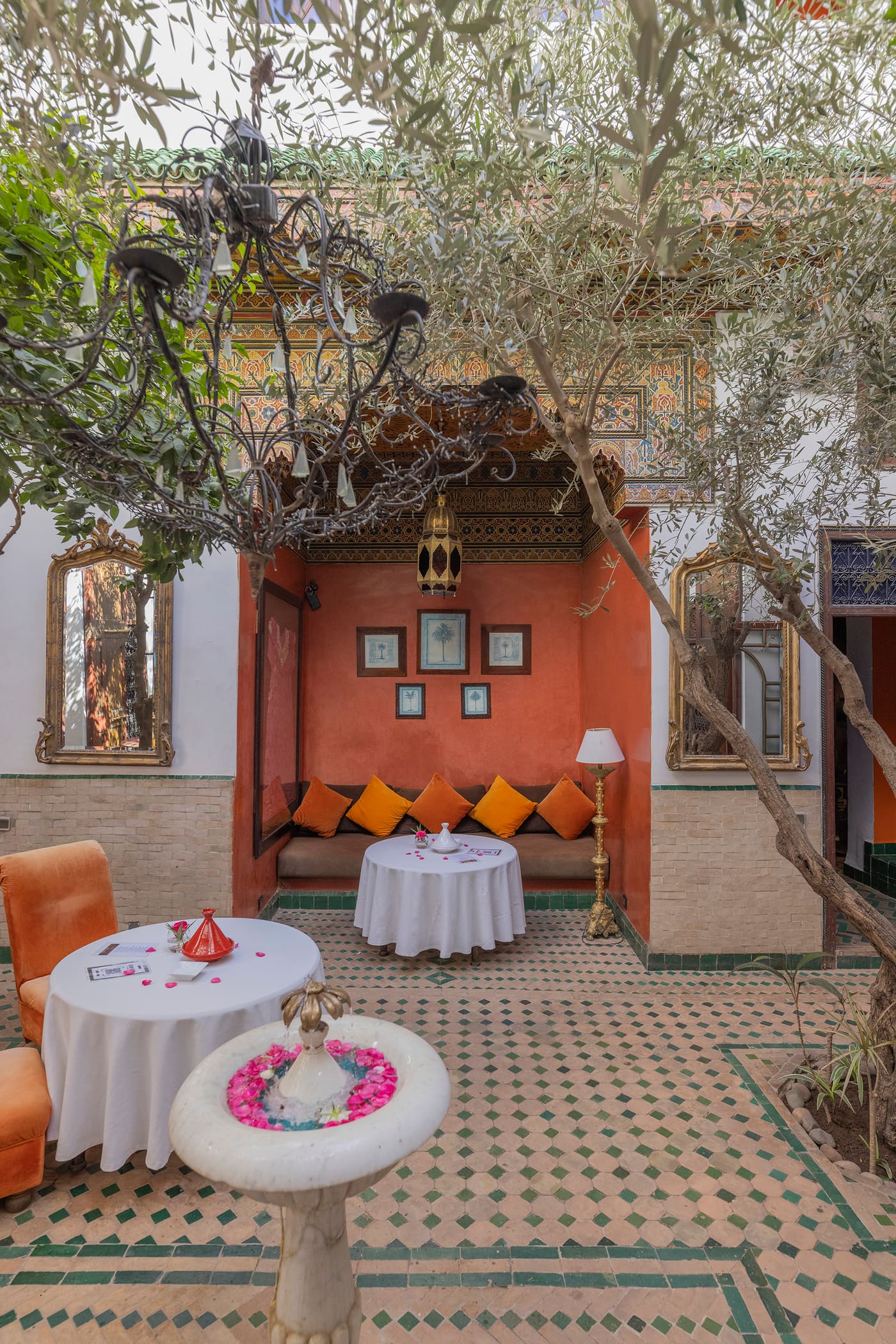 Un patio du riad en plein jour — arcades de chaux blanche, palmiers et zellige au sol